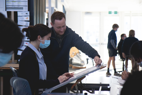 Technology teacher helping student with design work.